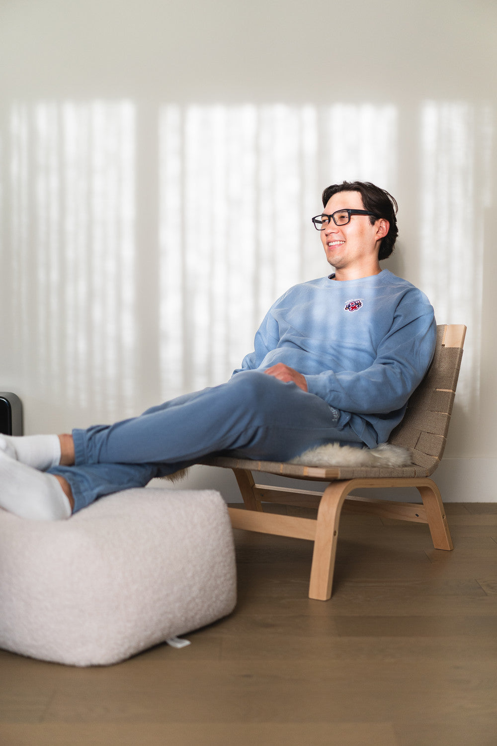 Person sitting on a wooden chair in a modern room with light-colored walls and flooring.