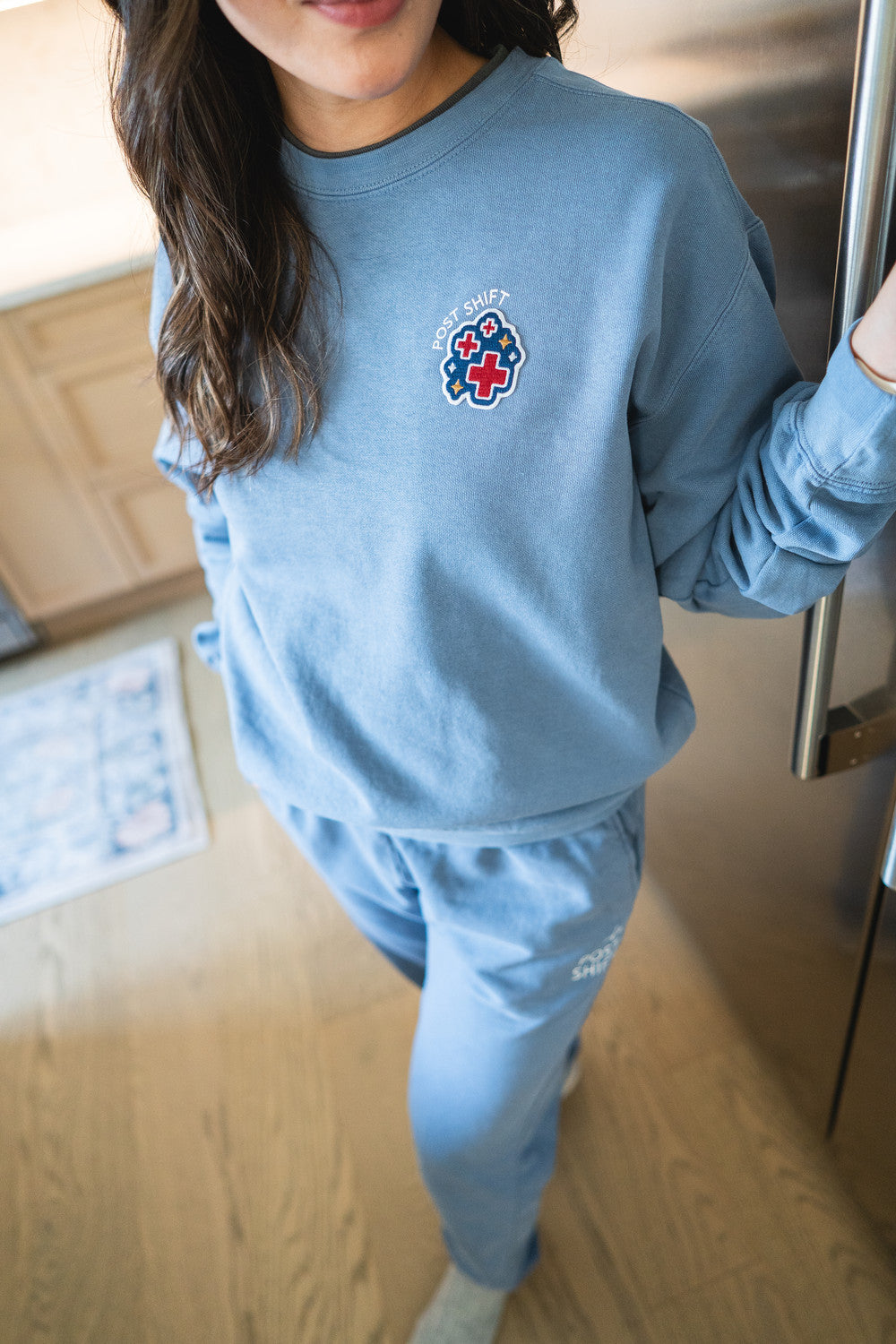 Person wearing a blue sweatshirt with a logo in a room.