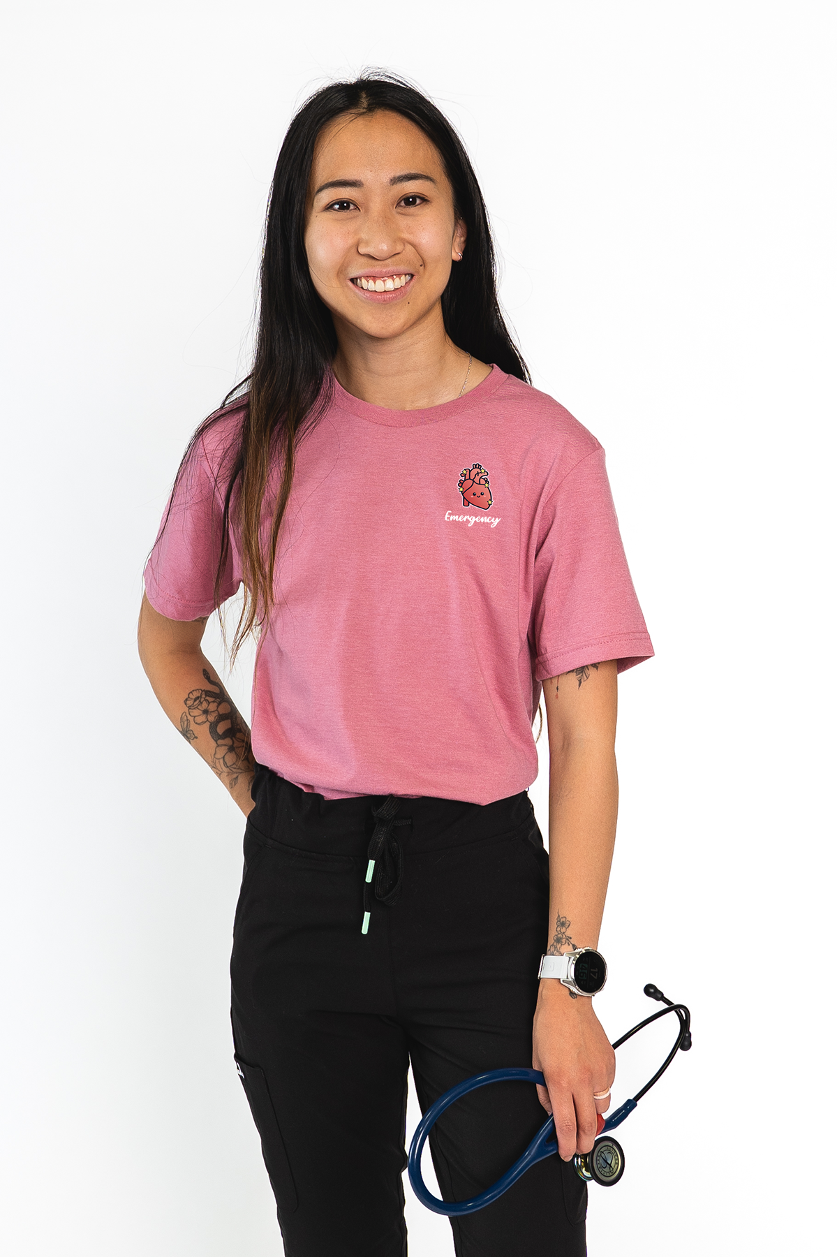 Person wearing a pink t-shirt with a logo and holding a stethoscope on a white background
