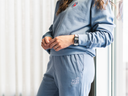Person wearing a blue tracksuit with 'Post Shift' branding, standing indoors.