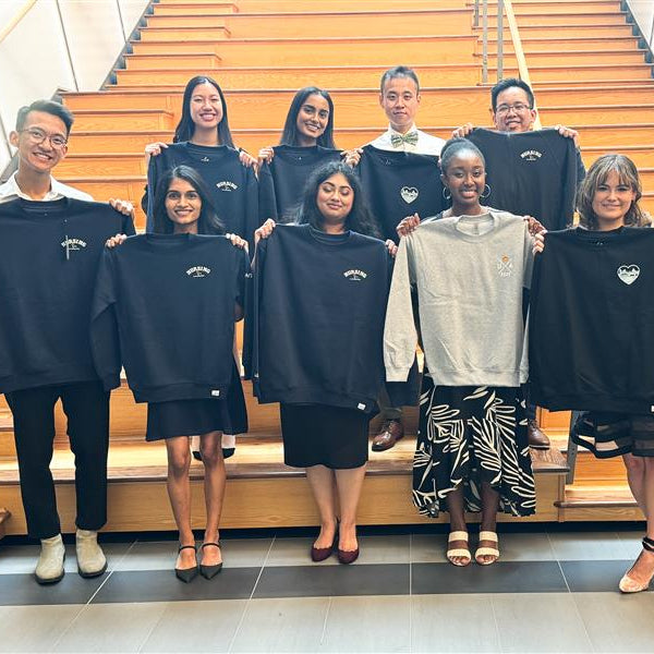 Group of people holding shirts in front of a staircase
